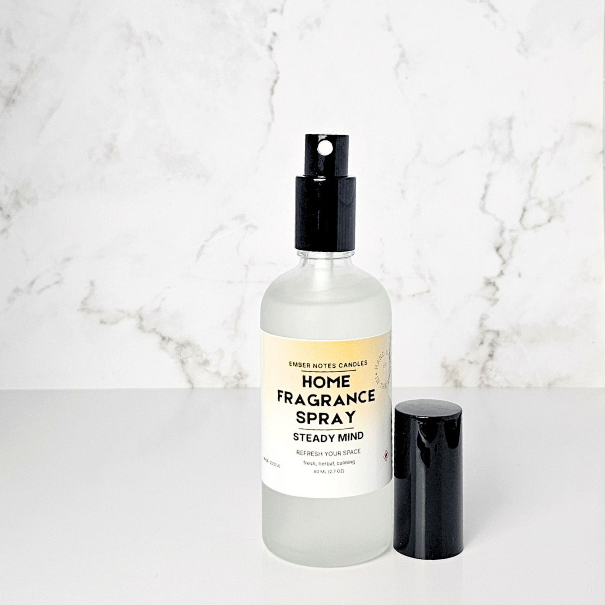 Home fragrance spray bottle with a yellow label on a marble surface