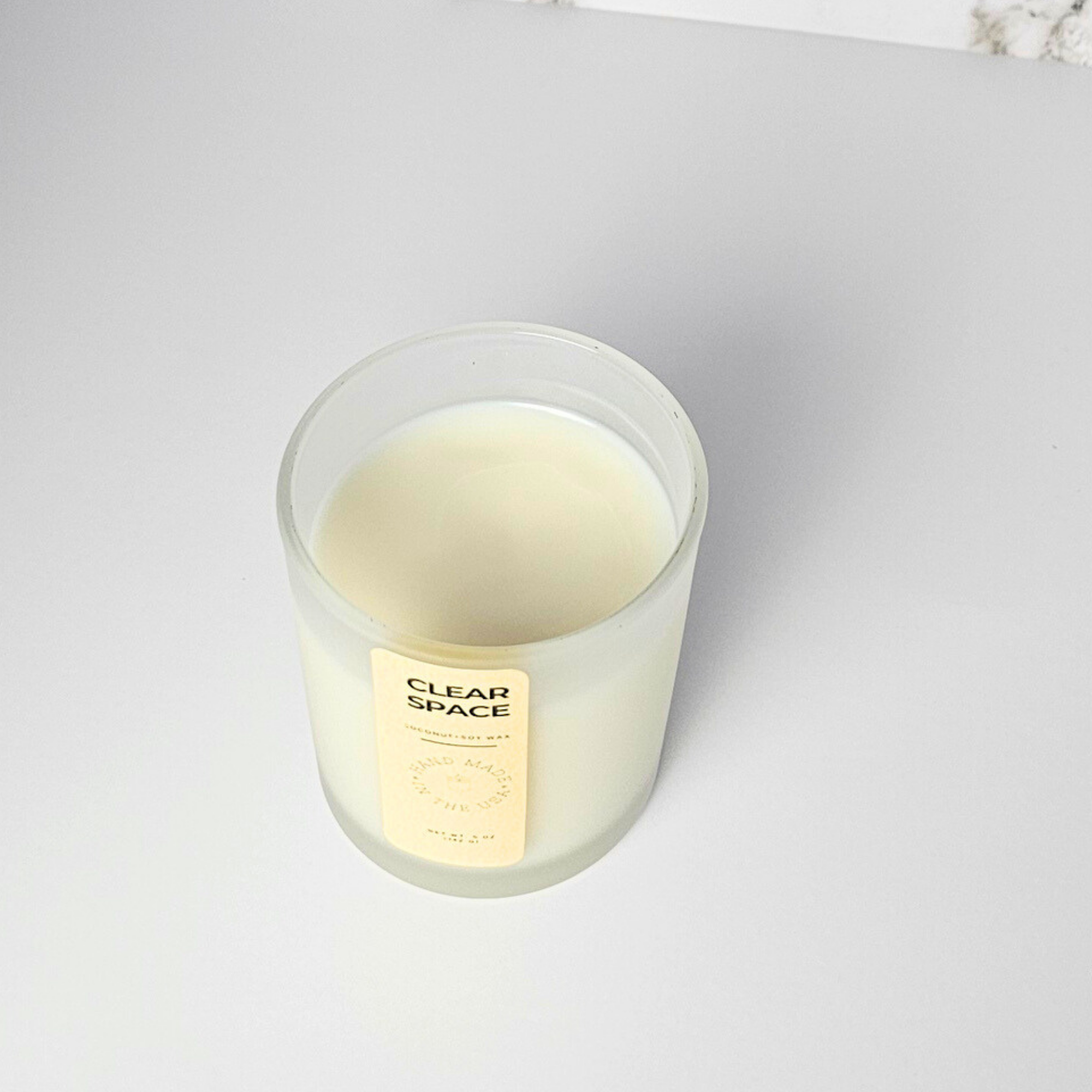 Clear glass wickless candle with a gold label on a white background