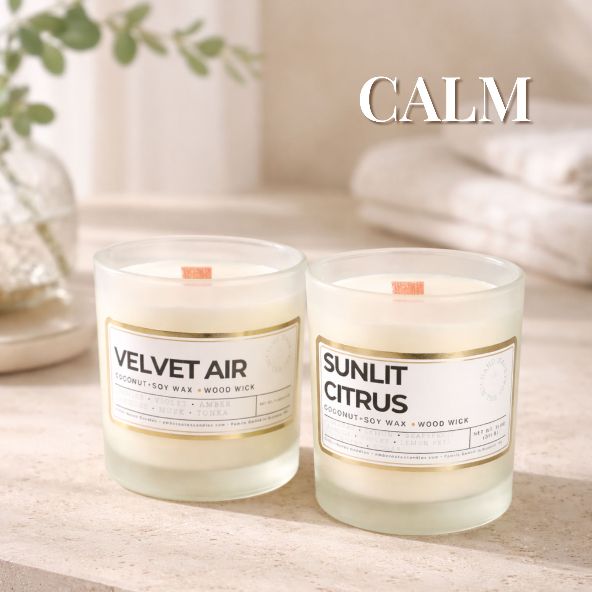 Two candles that are sitting on a table with bath towels behind them