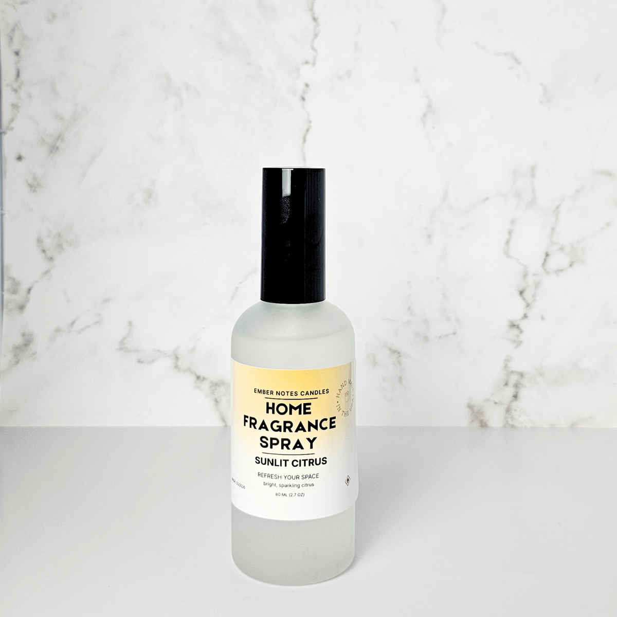 Home fragrance spray bottle with a yellow label on a marble background