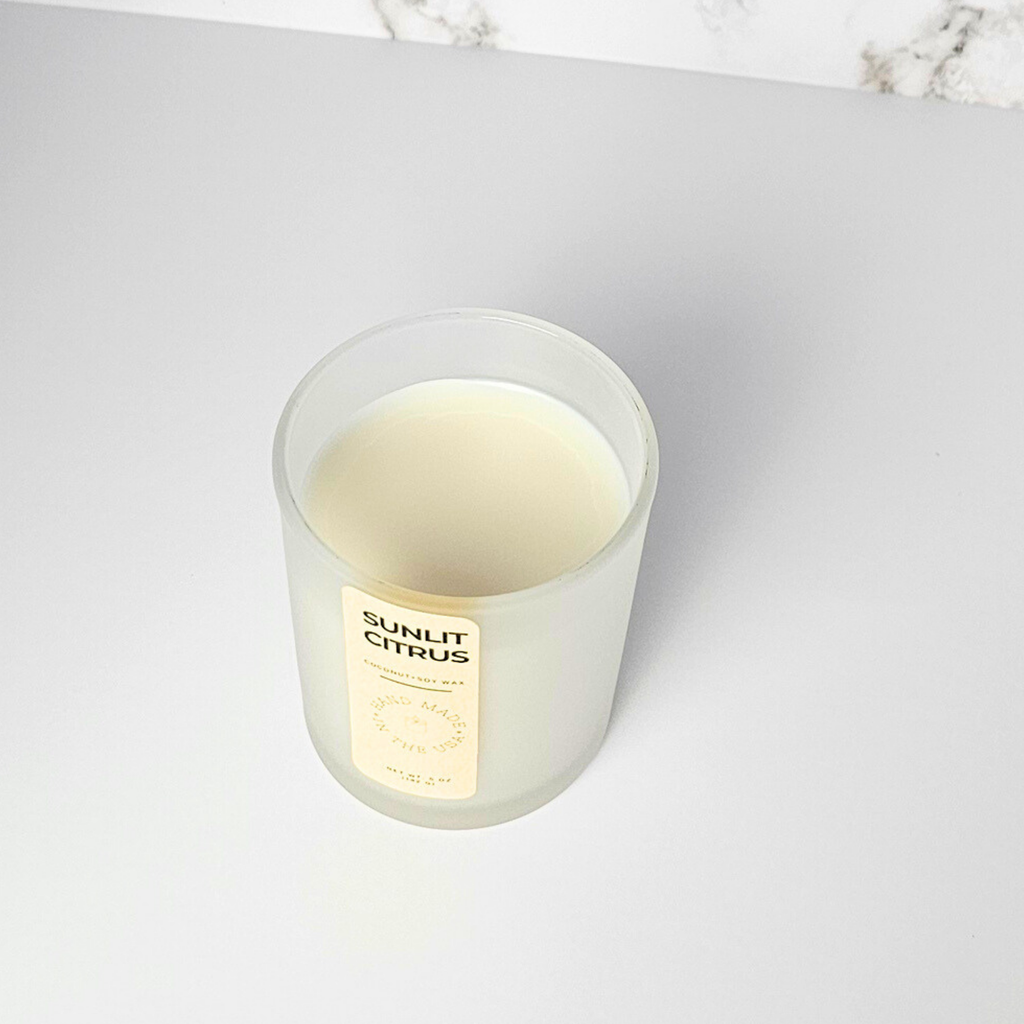 Candle labeled 'Sunlit Citrus' on a light gray surface