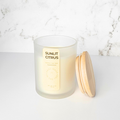 Candle labeled 'Sunlit Citrus' with a wooden lid on a marble surface