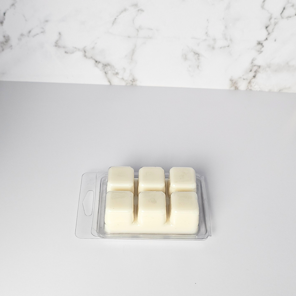 Cream-colored wax melts in a clear plastic packaging on a marble surface.